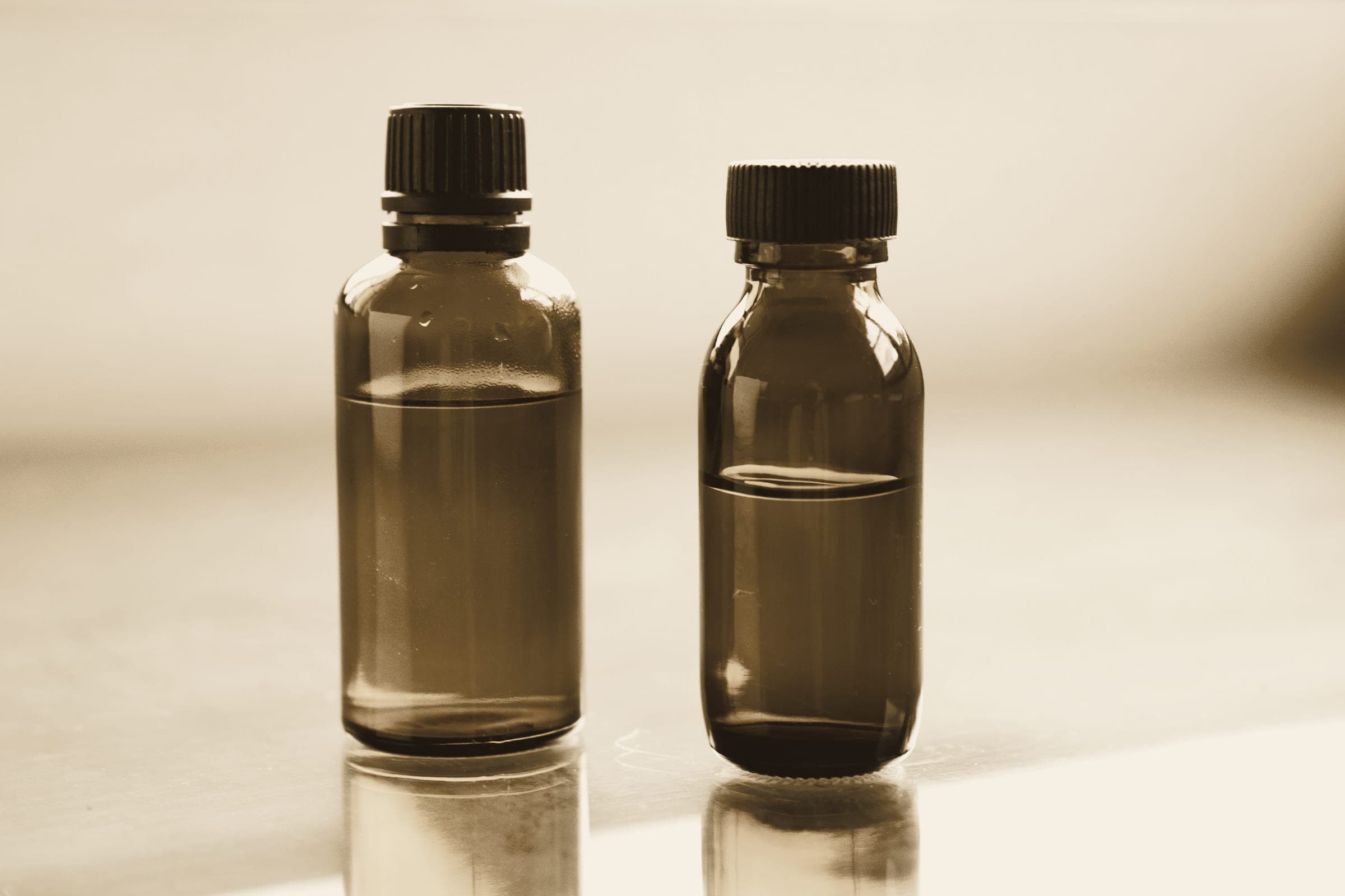 Two amber glass bottles standing side by side in soft daylight.