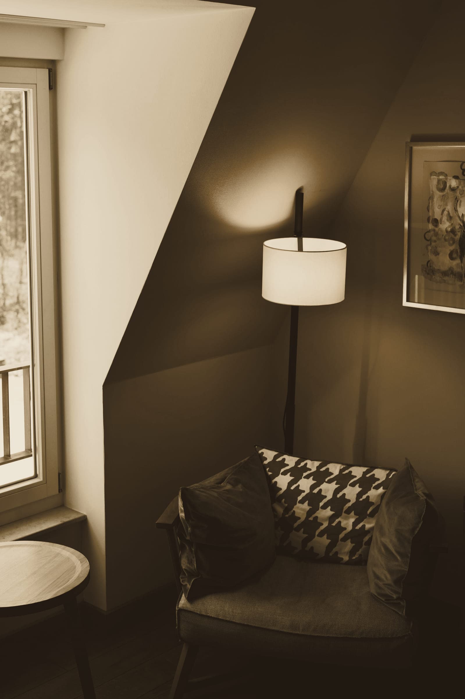A quiet corner with an armchair, a floor lamp and a small side table beside a window.