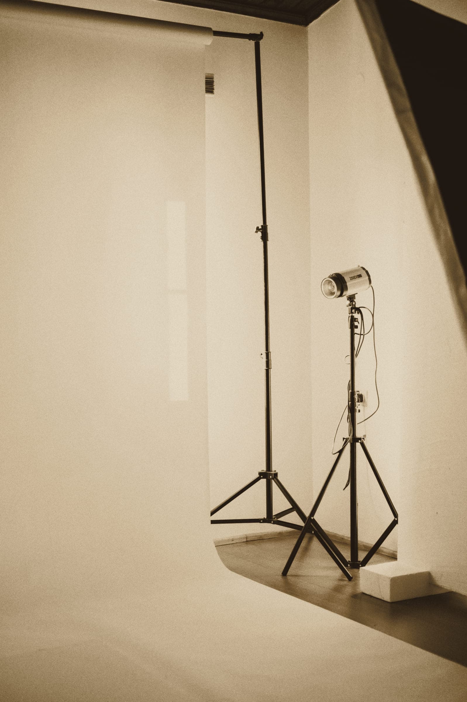 A plain white backdrop with a studio light on a stand.