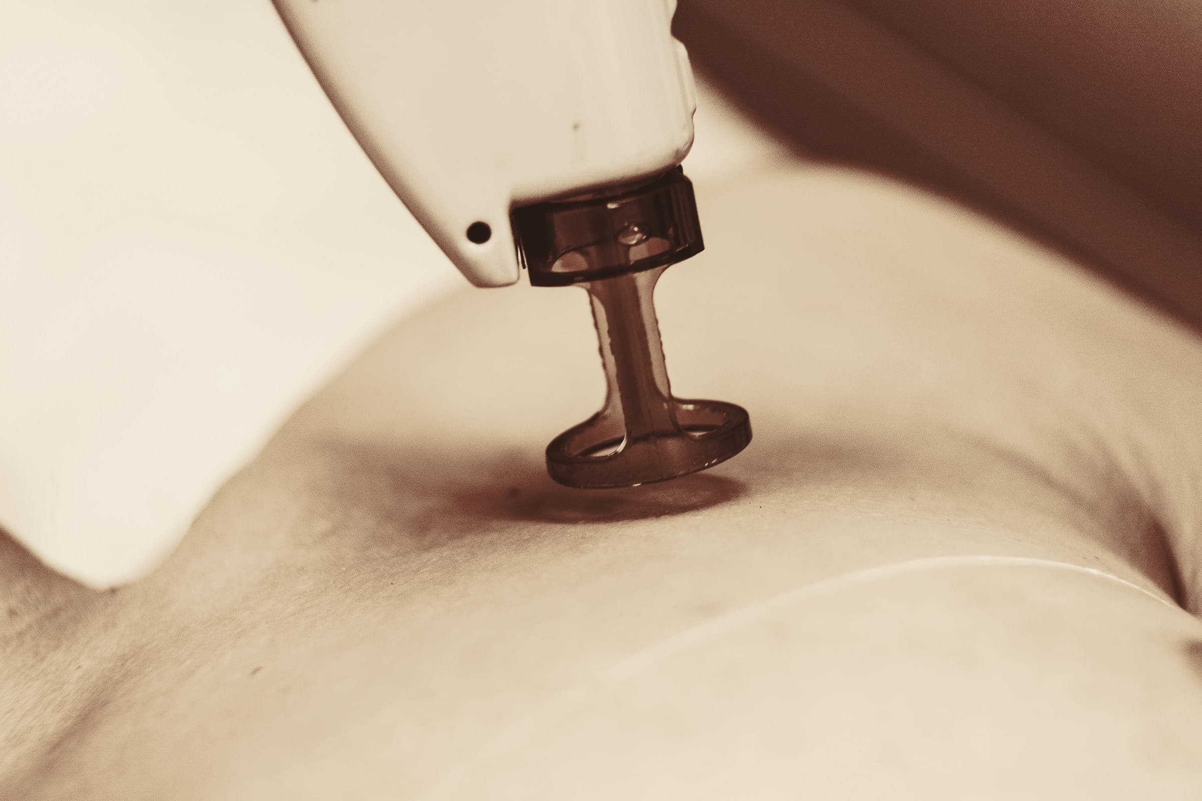 Close detail of a device handpiece with an amber tip resting against skin.