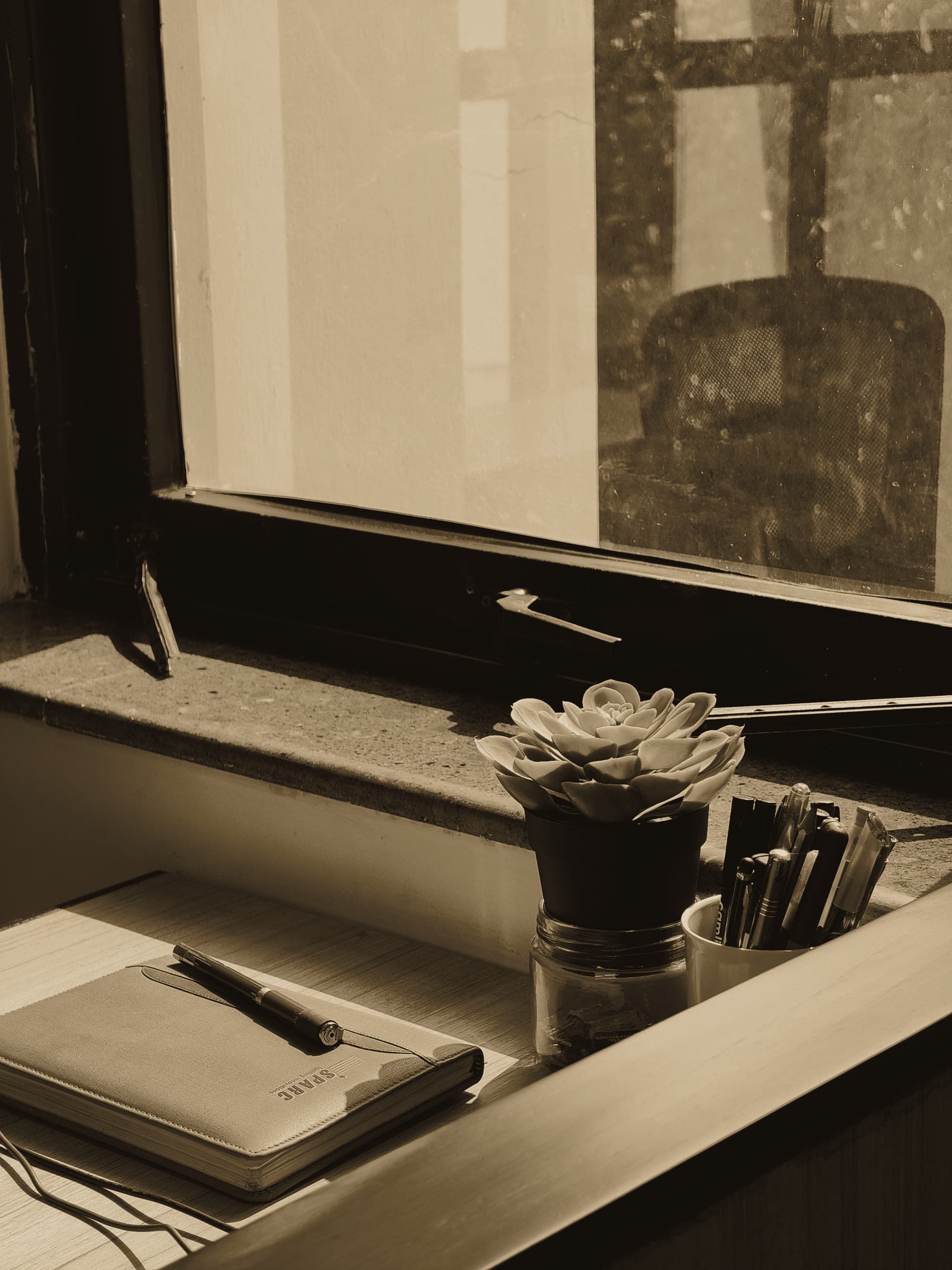 A notebook and pen on a windowsill desk in soft window light.