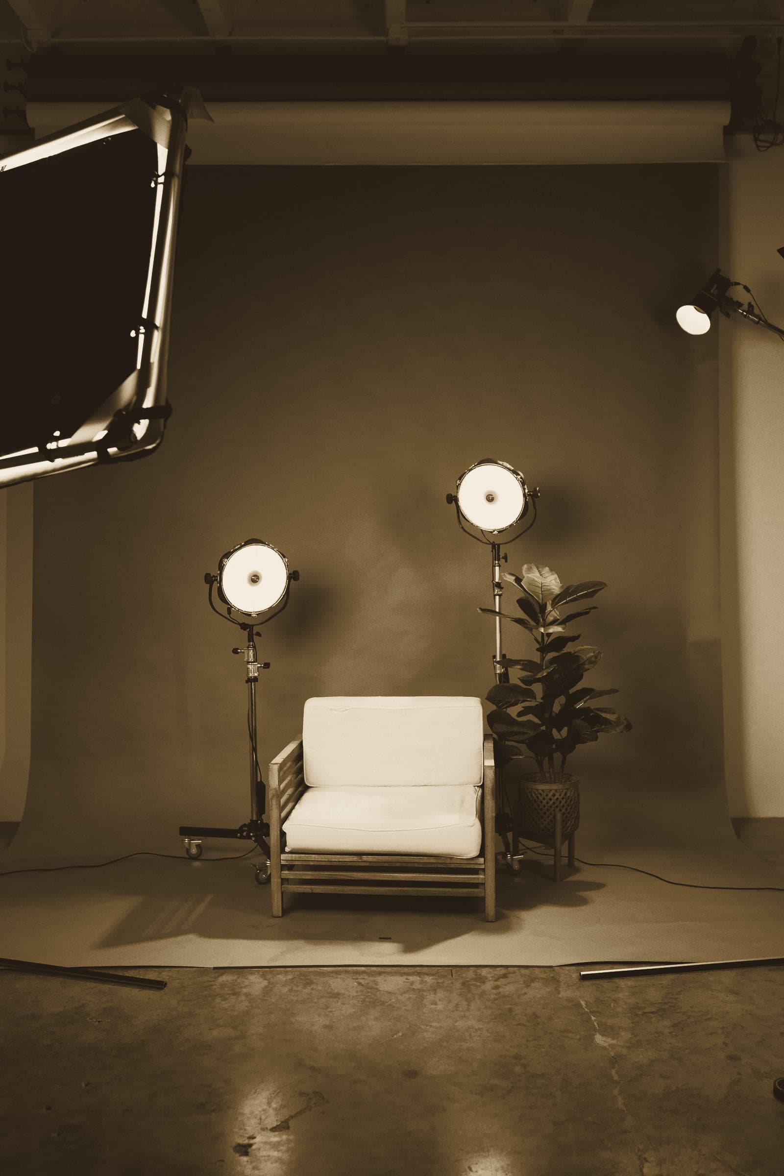 Two studio lights on stands either side of a chair against a neutral backdrop.