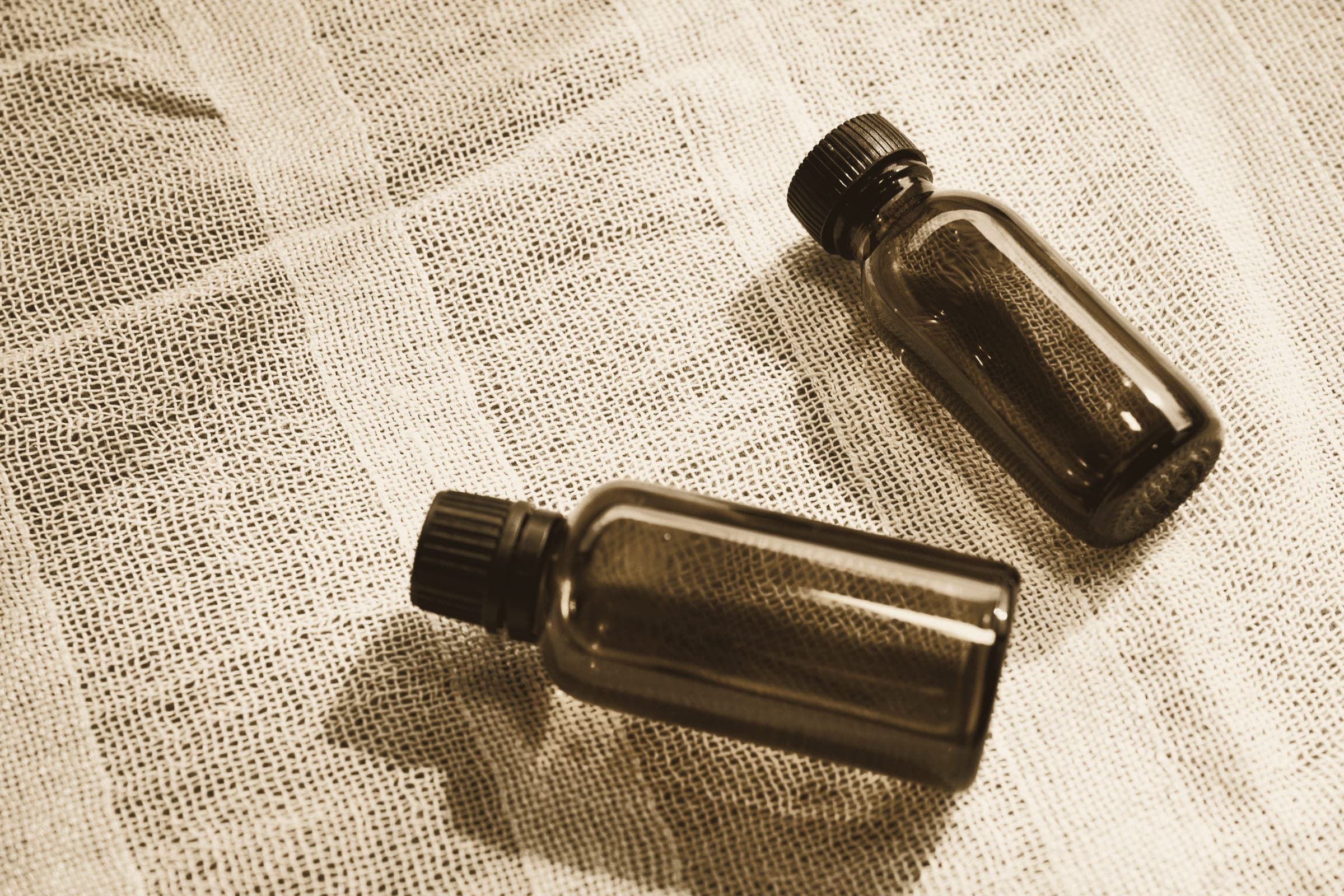 Two small amber glass bottles lying on folded linen in soft light.